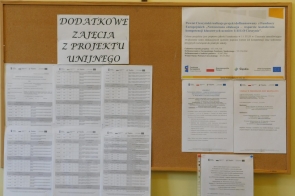 Tablica korkowa z harmonogramami i informacjami dotyczącymi dodatkowych zajęć z projektu unijnego, zawieszona na ścianie.