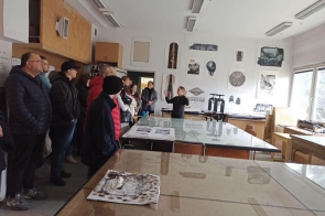 grupa uczestników zwiedzania w pracowni grafiki warsztatowej, słuchają panią Marynę Podolską
