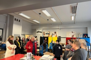 grupa uczestników zwiedzania w pracowni grafiki warsztatowej, słuchają panią Marynę Podolską