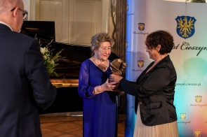 Janina Żagan Starosta Cieszyński wręcza statuetkę prof. Krystynie Heska-Kwaśniewicz, która ubrana jest w ciemno-niebieską, elegancką sukienkę. Obie Panie są uśmiechnięte. 