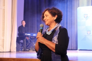 Janina Żagan, Starosta Cieszyński z mikrofonem w dłoni przemawia na scenie podczas Gali Sportu. W tle widoczny jest napis „Powiat Cieszyński” na niebieskim banerze.