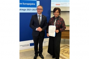 Janina Żagan, Starosta Cieszyński, odbiera list gratulacyjny z rąk Grzegorza Boskiego, Wicemarszałka Województwa Śląskiego. W tle plansza informująca o dofinansowaniu z Funduszy Europejskich i Województwa Śląskiego.