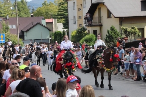 Jeźdźcy na ozdobionych kwiatami koniach prowadzą korowód dożynkowy ulicami Goleszowa, wśród tłumu uczestników i widzów.
