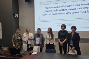 W sali konferencyjnej, przed ekranem z prezentacją, stoi sześć kobiet w półformalnych strojach, część z identyfikatorami. Na slajdzie: „Podsumowanie Wojewódzkiego Konkursu ‘Nowe technologie, nowe możliwości – konkurs na innowacyjny scenariusz lekcji’”. Trzy osoby trzymają dyplomy i torby .