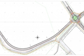 Duży rysunek techniczny drogi. Od lewego górnego rogu biegnie nowy łącznik ulicy – czarna jezdnia skręcająca szerokim łukiem w dół i w prawo – kończący się rondem po prawej z zielonym środkiem i czterema wlotami. Kolorowe linie pokazują chodniki, ścieżkę pieszo-rowerową, krawężniki, wyspy i odwodnienie; w lewym górnym rogu zarys budynków, na środku różę wiatrów. Po prawej widoczna legenda oznaczeń i tabelka z danymi projektu.