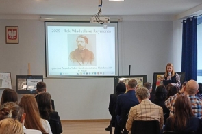 Kilka dłoni trzyma zapakowane w folię małe drewniane krążki. Na każdym krążku znajduje się wypalony wizerunek postaci. Ozdoby są przewiązane czerwonymi wstążkami.