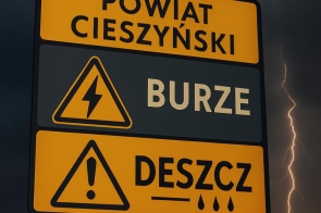 Znak ostrzegawczy z napisem „Powiat Cieszyński” informuje o niebezpiecznych zjawiskach pogodowych: burzach (ikona błyskawicy) i intensywnym deszczu (ikona kropli). W tle widać ciemne chmury, błyskawicę i padający deszcz.