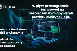 Sylwetka osoby w kapturze pracującej na laptopie, z zielonym kodem wyświetlonym na ekranie, na tle cyfrowej grafiki. Po lewej stronie logo Policji i tekst informujący o wpływie cyberprzestępczości na bezpieczeństwo mieszkańców powiatu cieszyńskiego.
