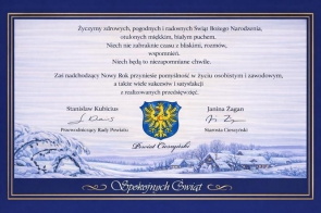 Granatowo-złota ramka otacza jasne tło z życzeniami świątecznymi. Pod tekstem w centrum widnieje herb Powiatu Cieszyńskiego z napisem „Powiat Cieszyński”. Po lewej jest podpis Stanisława Kubiciusa z tytułem, po prawej podpis Janiny Żagan z tytułem. Dół zajmuje malowany zimowy pejzaż wsi w śniegu oraz napis „Spokojnych Świąt”.