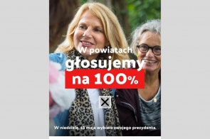 Uśmiechnięte kobiety stoją na tle zieleni. Na środku widnieje tekst: "W powiatach głosujemy na 100%". Na dole napis: "W niedzielę, 18 maja wybierz swojego prezydenta". Znajdują się tam też loga organizacji, w tym Unii Metropolii Polskich.