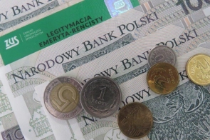 Polskie banknoty i monety różnych nominałów ułożone pod zieloną legitymacją emeryta-rencisty ZUS. W tle widoczny napis „Narodowy Bank Polski” na banknotach stuzłotowych.