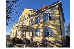 Budynek Zespołu Szkół Przyrodniczo - Technicznych w Międzyświeciu w słoneczny dzień. Budynek jasno żółtego koloru. 