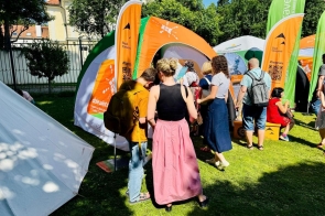 Zdjęcie przedstawia osoby przy stoisku Śląska Cieszyńskiego w ogrodach Ambasady RP w Pradze, zainteresowane ofertą turystyczo-kulturalną regionu .