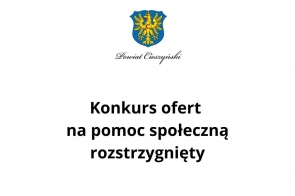 Herb Powiatu Cieszyńskiego na górze, pod nim napis "Powiat Cieszyński" w eleganckiej czcionce. Centralnie umieszczony tekst informuje: "Konkurs ofert na pomoc społeczną rozstrzygnięty". Białe tło.
