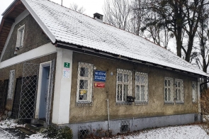 Domek Ogrodnika – Muzeum Zofii Kossak-Szatkowskiej w Górkach Wielkich od strony ulicy/wejścia, niewielki zabytkowy budynek z jasną elewacją, spadzistym dachem pokrytym śniegiem oraz oknami zabezpieczonymi kratami, listopad 2025.
