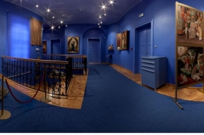 W muzealnej sali o niebieskich ścianach znajdują się obrazy i rzeźby prezentowane na ścianach oraz na stojakach. Wnętrze oświetlone jest punktowymi lampami w suficie, a wzdłuż balkonu biegnie metalowa balustrada. Na dole widoczne są logotypy programów Ministra Kultury i Dziedzictwa Narodowego.