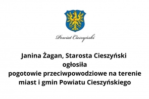Herb Powiatu Cieszyńskiego i napis „Janina Żagan, Starosta Cieszyński ogłosiła pogotowie przeciwpowodziowe na terenie miast i gmin Powiatu Cieszyńskiego.” Komunikat informuje o podjętych działaniach w związku z zagrożeniem powodziowym.