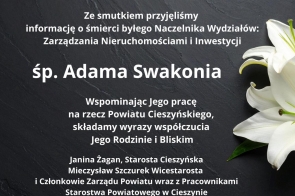 Czarny kamienny blat z delikatnie widocznym fragmentem białej lilii po prawej stronie oraz białym tekstem kondolencyjnym informującym o śmierci śp. Adama Swakonia, wraz z wyrazami współczucia od władz i pracowników Starostwa Powiatowego w Cieszynie.