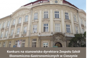 Zdjęcie przedstawia Zespół Szkół Ekonomiczno-Gastronomicznych w Cieszynie, to zabytkowy budynek z jasną elewacją, licznymi oknami i zdobioną fasadą. Nad wejściem głównym widnieje zegar. Na dole umieszczono informację o konkursie na stanowisko dyrektora Zespołu Szkół Ekonomiczno-Gastronomicznych w Cieszynie