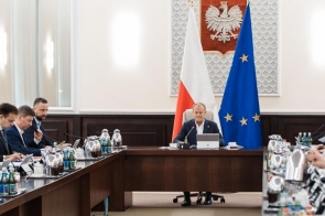  Premier Donald Tusk i ministrowie podczas posiedzenia Rady Ministrów w sali konferencyjnej. Na ścianie godło Polski oraz flaga narodowa i Unii Europejskiej.