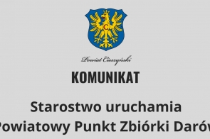  Herb Powiatu Cieszyńskiego oraz napis: "Komunikat. Starostwo uruchamia Powiatowy Punkt Zbiórki Darów." na szarym tle, informacja o pomocy dla potrzebujących.