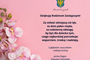 Różowe tło, z lewej strony gałązka storczyków. Po prawej herb Powiatu Cieszyńskiego, pod nim podziękowanie dla rodzin zastępczych z podpisem Starosty Janiny Żagan, w eleganckim granatowym kroju pisma.