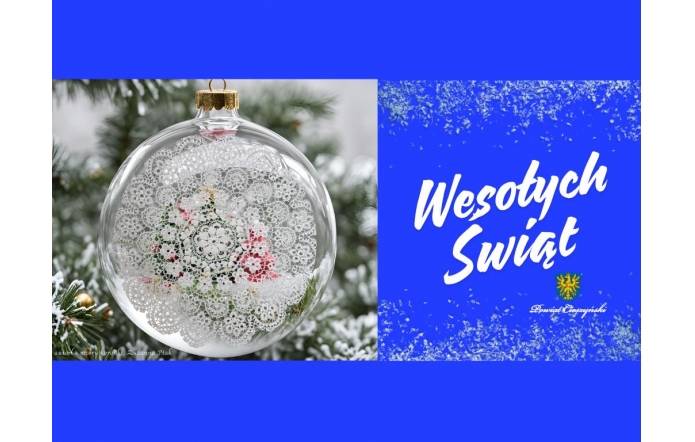 Obraz przedstawia przezroczystą bombkę zdobioną koronkowym wzorem, w tle widoczne gałązki świerku pokryte śniegiem. Po prawej stronie znajduje się intensywnie niebieskie tło z białym napisem „Wesołych Świąt” oraz herbem w złoto-zielonych barwach i nazwą „Powiat Cieszyński” poniżej.