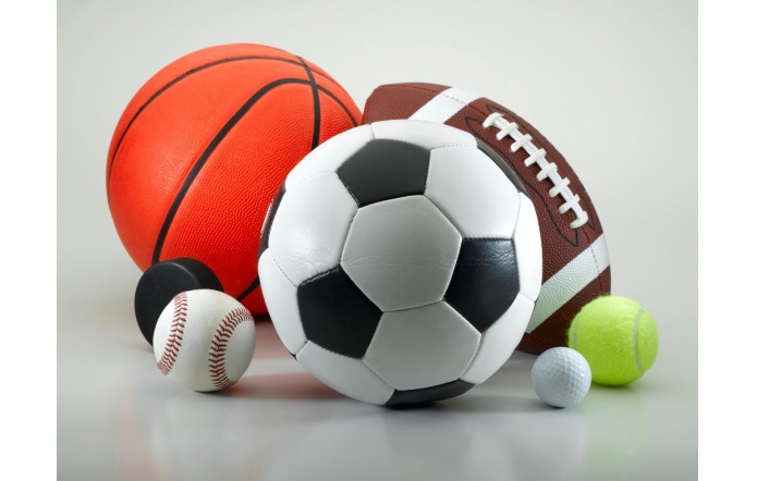 Grafika przedstawia leżące na białym tle, blisko siebie, piłki różnej wielkości. Od lewej na pierwszym planie leży mały czarny krążek hokejowy, mała biała piłka do baseballa z czerwonymi przeszyciami, duża piłka do gry w piłkę nożną w czarno białe łaty, mała biała piłeczka golfowa,mała jasnożółta piłka tenisowa. Na drugim planie duża brązowa piłka do rugby oraz duża pomarańczowa piłka do koszykówki. 
