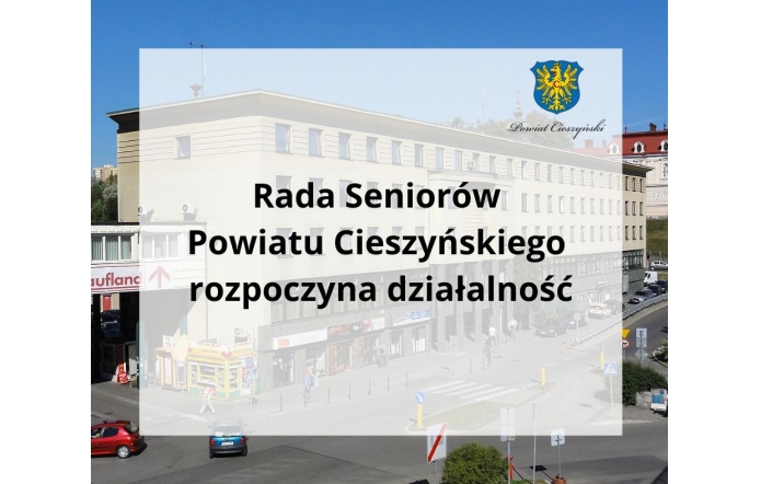 Widoczny jest budynek Starostwa Powiatowego w Cieszynie z główną ulicą i pieszymi na pierwszym planie. Na półprzezroczystym tle umieszczono napis: „Rada Seniorów Powiatu Cieszyńskiego rozpoczyna działalność”.