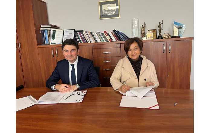 Wojewoda Śląski Marek Wójcik i Janina Żagan Starosta Cieszyński podpisują umowę przy stole w gabinecie starosty.