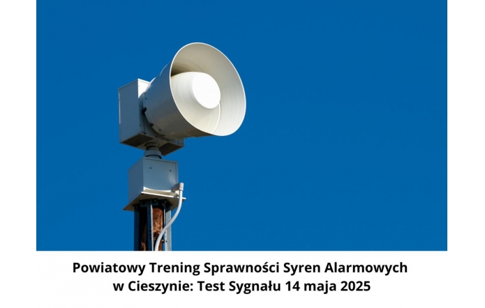 Syrena alarmowa zamontowana na słupie, skierowana w lewą stronę, na tle czystego, niebieskiego nieba. W dolnej części obrazka znajduje się informacja o powiatowym treningu syren alarmowych w Cieszynie.