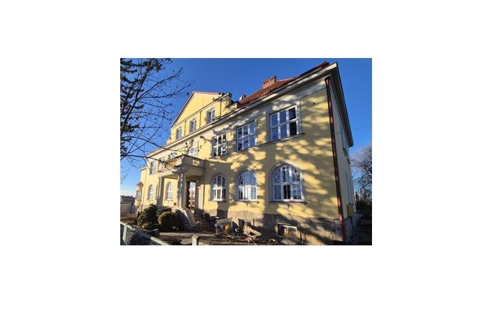 Budynek Zespołu Szkół Przyrodniczo - Technicznych w Międzyświeciu w słoneczny dzień. Budynek jasno żółtego koloru. 