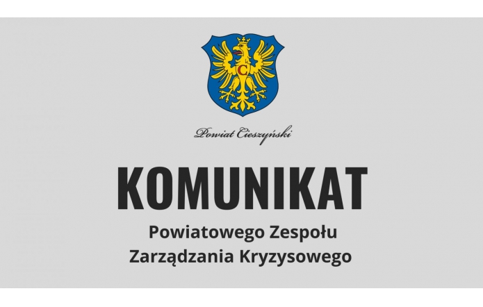 Herb Powiatu Cieszyńskiego oraz duży napis „KOMUNIKAT Powiatowego Zespołu Zarządzania Kryzysowego.” Grafika dotyczy ogłoszenia o charakterze informacyjnym dla mieszkańców powiatu.