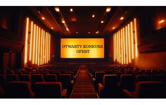 Grafika przedstawia wnętrze kina. W centralnej części widoczny ekan z żółtym tłem na którym widnieje napis: otwarty konkurs ofert. Po lewej i po prawej stronie rzędy niskich siedzeń. Na ścianach pionowe lampy oświetlające żółtym ciepłym światłem półmrok sali.