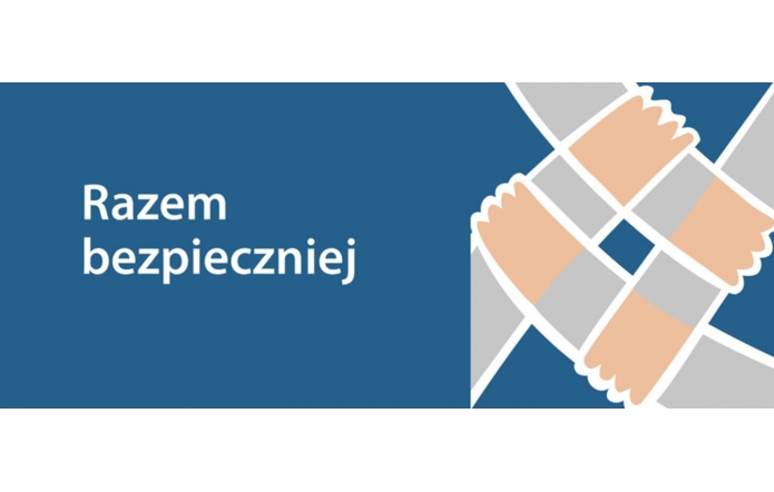 Granatowe tło, po lewej stronie biały napis „Razem bezpieczniej”, po prawej stylizowane grafiki splecionych rąk tworzących symbol współpracy i wsparcia. Całość przekazuje ideę wspólnego działania na rzecz bezpieczeństwa.