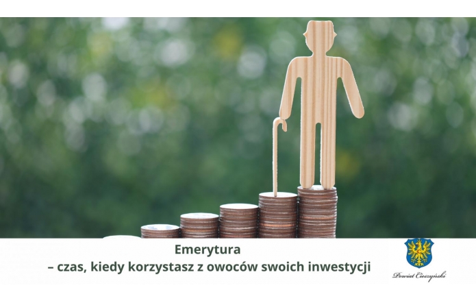 Drewniana sylwetka starszej osoby z laską stoi na szczycie rosnących stosów monet, symbolizujących gromadzone przez lata oszczędności. Hasło: „Emerytura – czas, kiedy korzystasz z owoców swoich inwestycji”. W rogu herb Powiatu Cieszyńskiego.