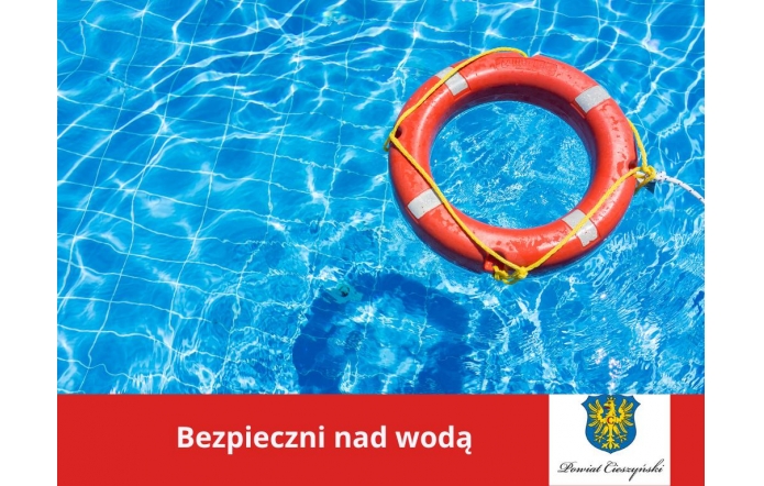 ChatGPT powiedział: Jasnoniebieska woda basenu z delikatnymi refleksami słońca, po której unosi się pomarańczowe koło ratunkowe z białymi odblaskami i żółtą liną. W dolnej części grafiki czerwony pasek z napisem „Bezpieczni nad wodą” oraz herbem i logotypem Powiatu Cieszyńskiego.